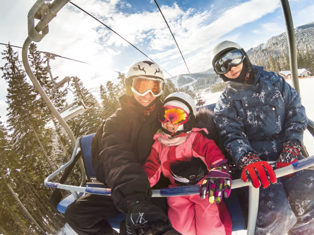 happy smiling family skiers on ski lift making selfie