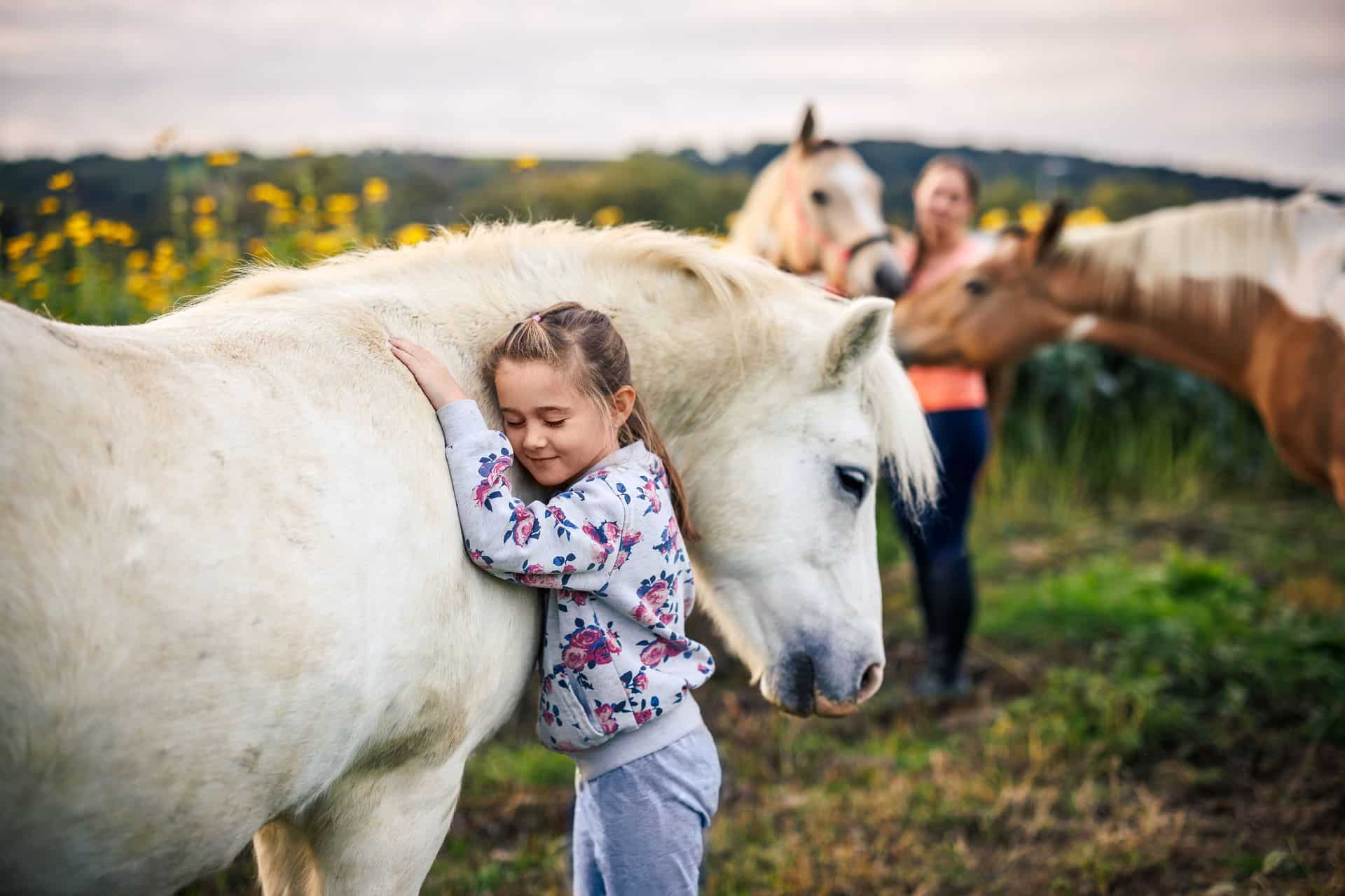 Niña rodeada de animales y un caballo en una escapada a la montaña con su familia