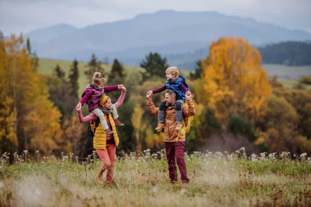 Niños caminando por una ruta de montaña en otoño con árboles de hojas amarillas