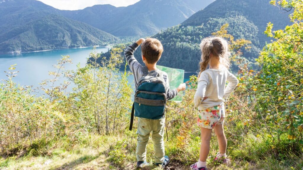 Dos niños de espaldas mirando un lago de montaña durante una excursión familiar