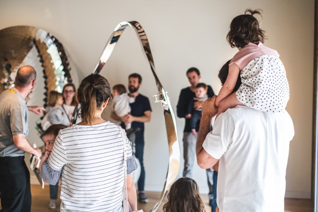 Familias con niños escuchando a la guía junto a una escultura de acero en la visita guiada familiar del CAHH