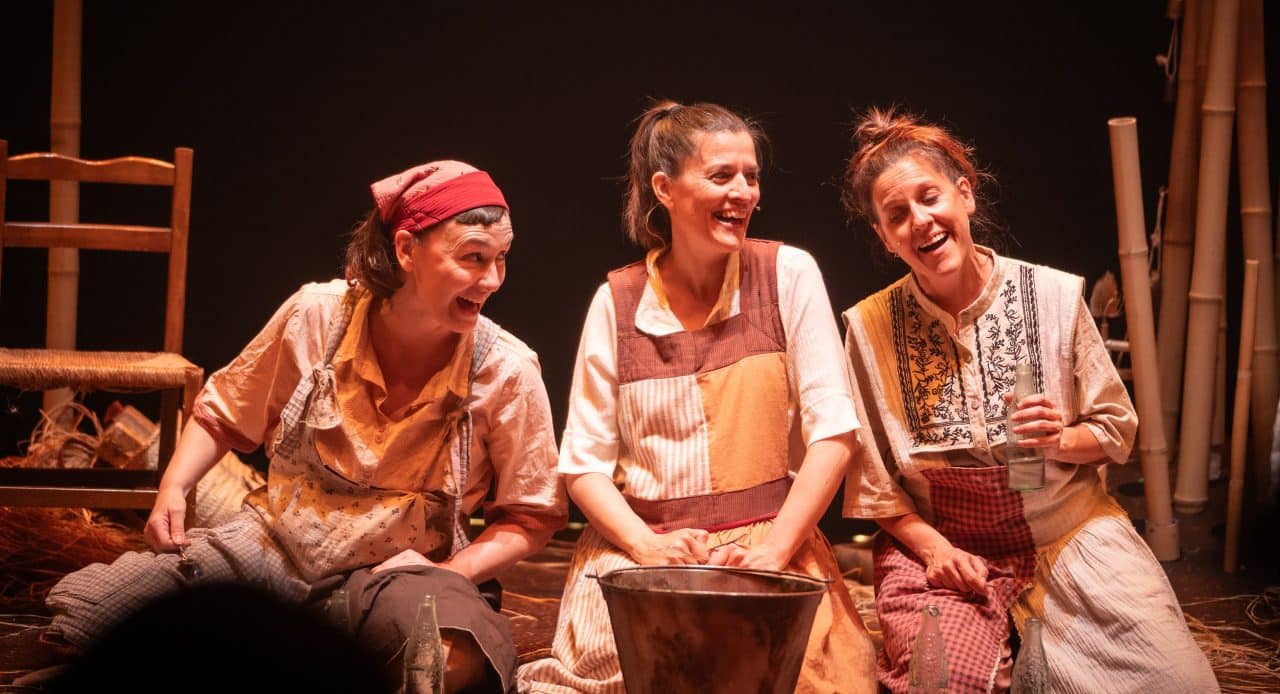 Tres actrices riendo sentadas entre paja y cañas en Nallar, teatro para bebés del Escalante