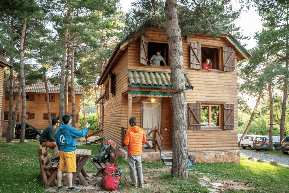 Niños jugando junto a una cabaña de madera entre los pinos en El Xalet de Prades